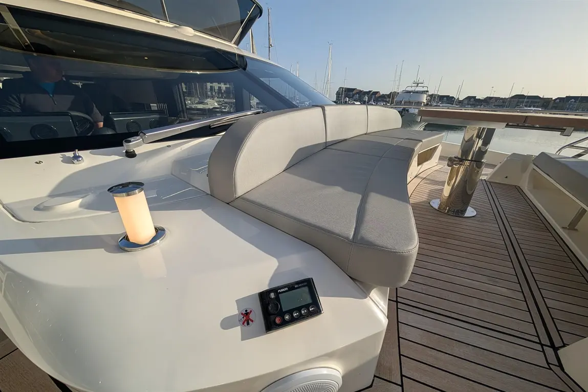 Luxury motorboat cockpit with sleek seating, glass cockpit, and modern controls. Sunlight reflects off polished surfaces.